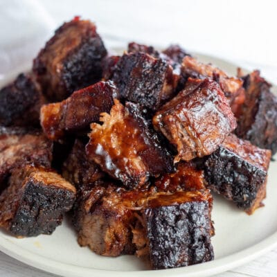 BBQ brisket burnt ends stacked on white plate and served.