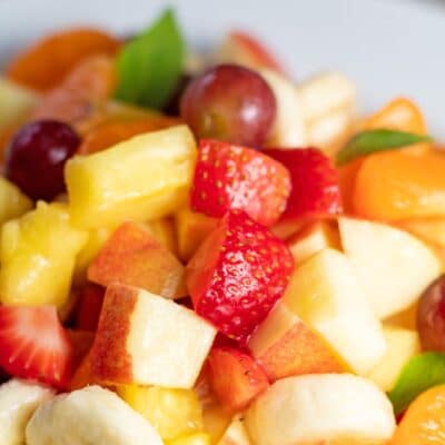Pin image with text of fruit cocktail salad in a white dish.