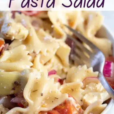 Pin image of a white bowl full of Greek pasta salad.