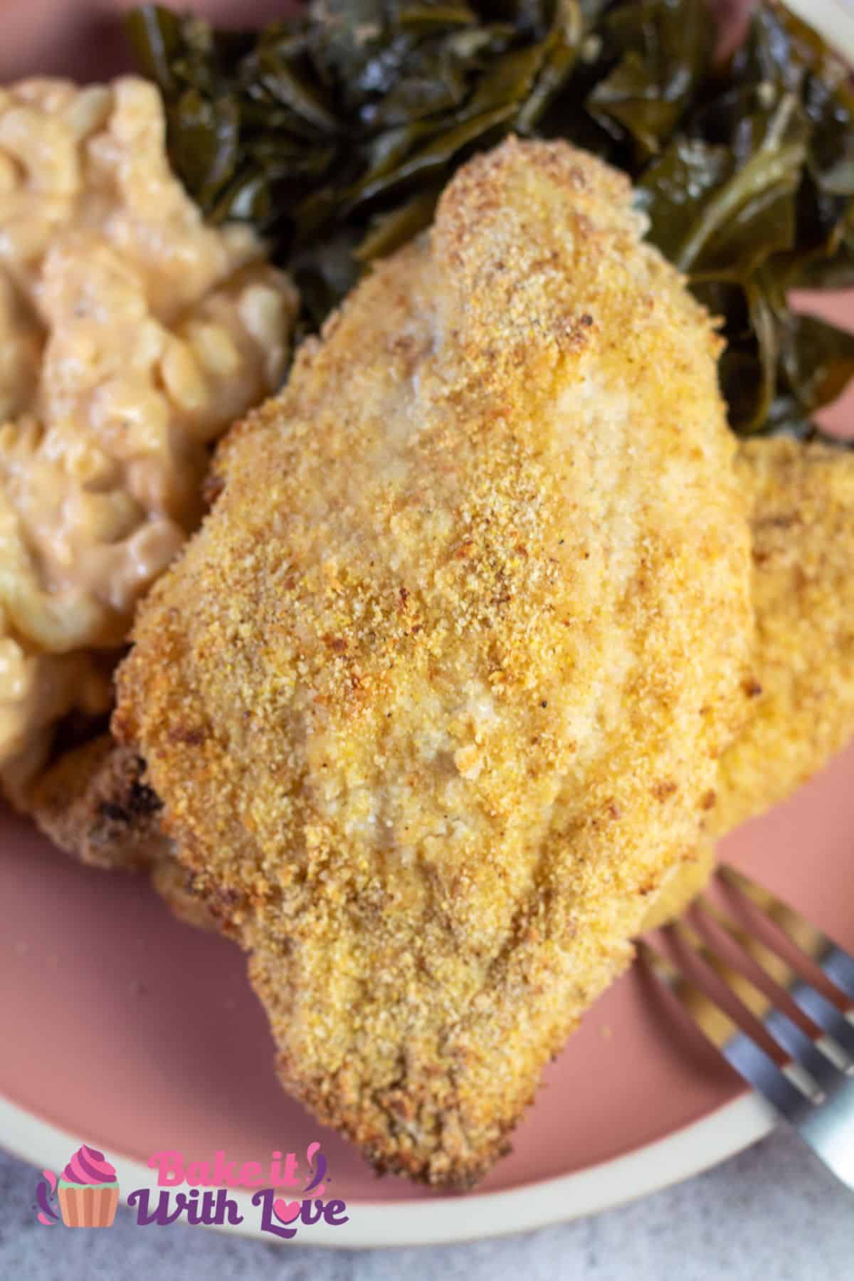 Tall closeup on the oven fried catfish fillets on plate with mac n cheese and collard greens.
