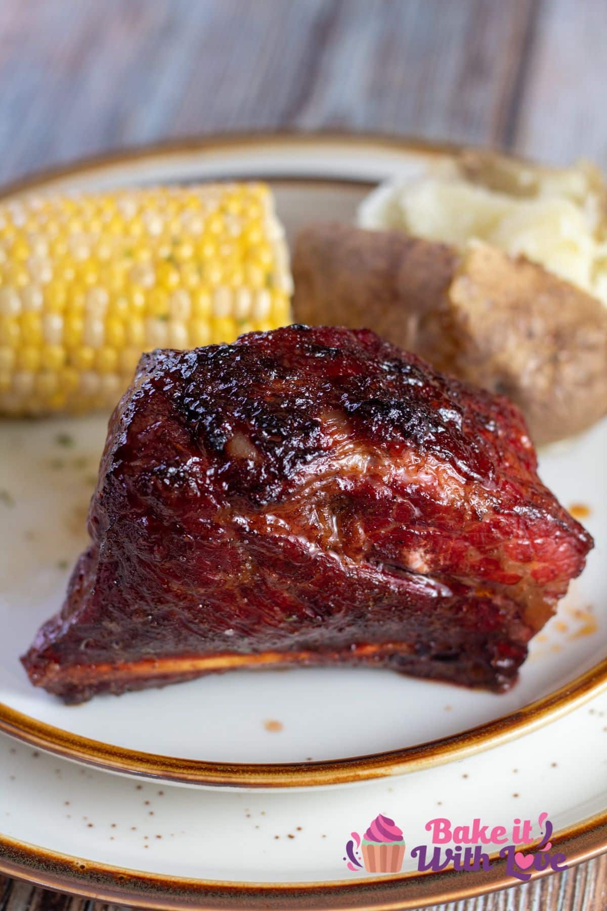 Tall image of the smoked short ribs served up with baked potato and corn on the cob.