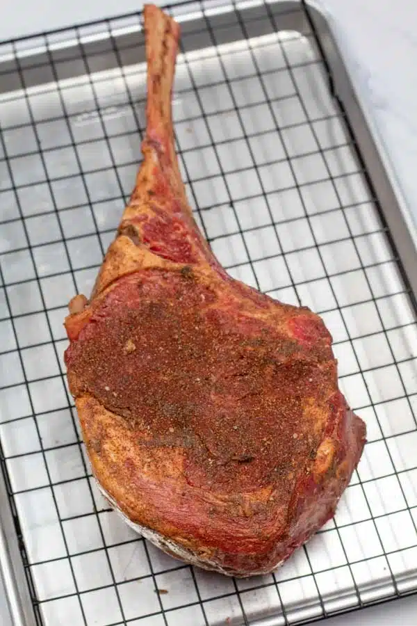 Process photo 1 showing tomahawk steak with seasoning.