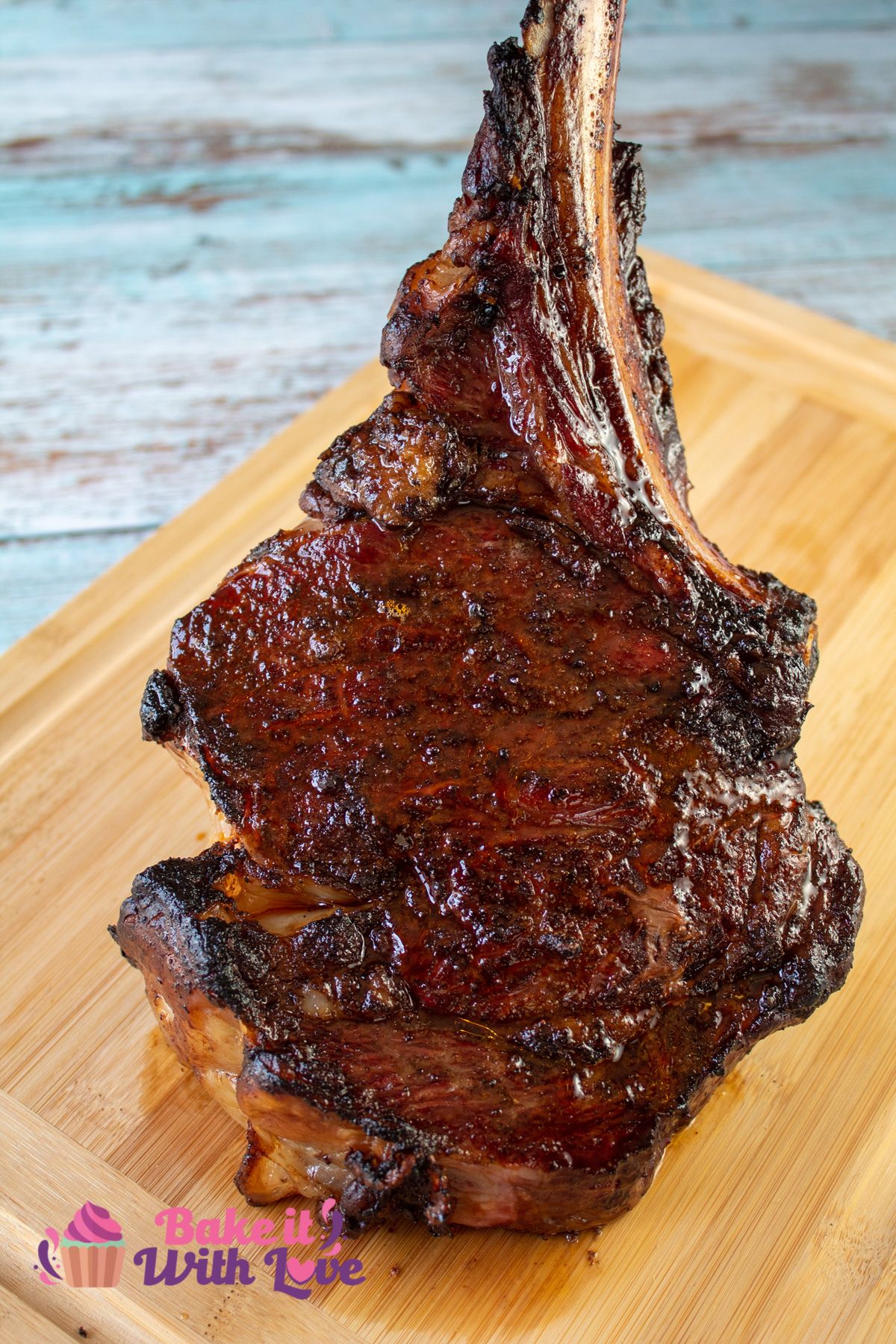 Tall image of smoked tomahawk steak on a cutting board.