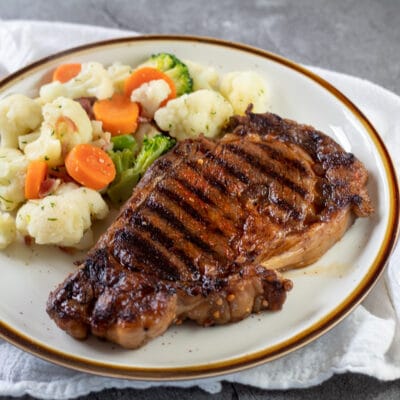La mejor receta de adobo de bistec eleva tus bistecs a la parrilla como este tierno chuletón servido con verduras mixtas.
