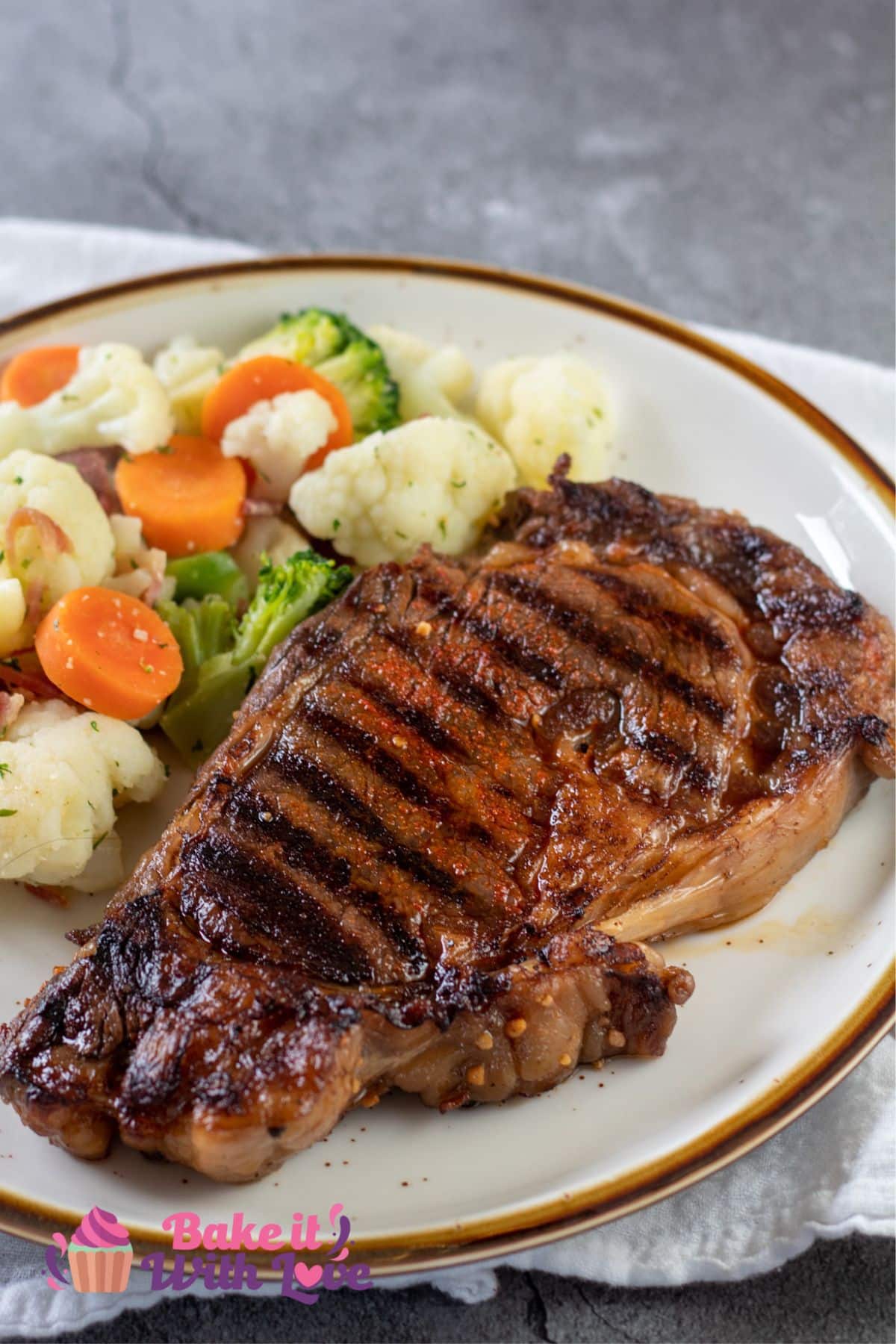 Tender grilled ribeye with steak marinade served on tan plate with veggie blend.