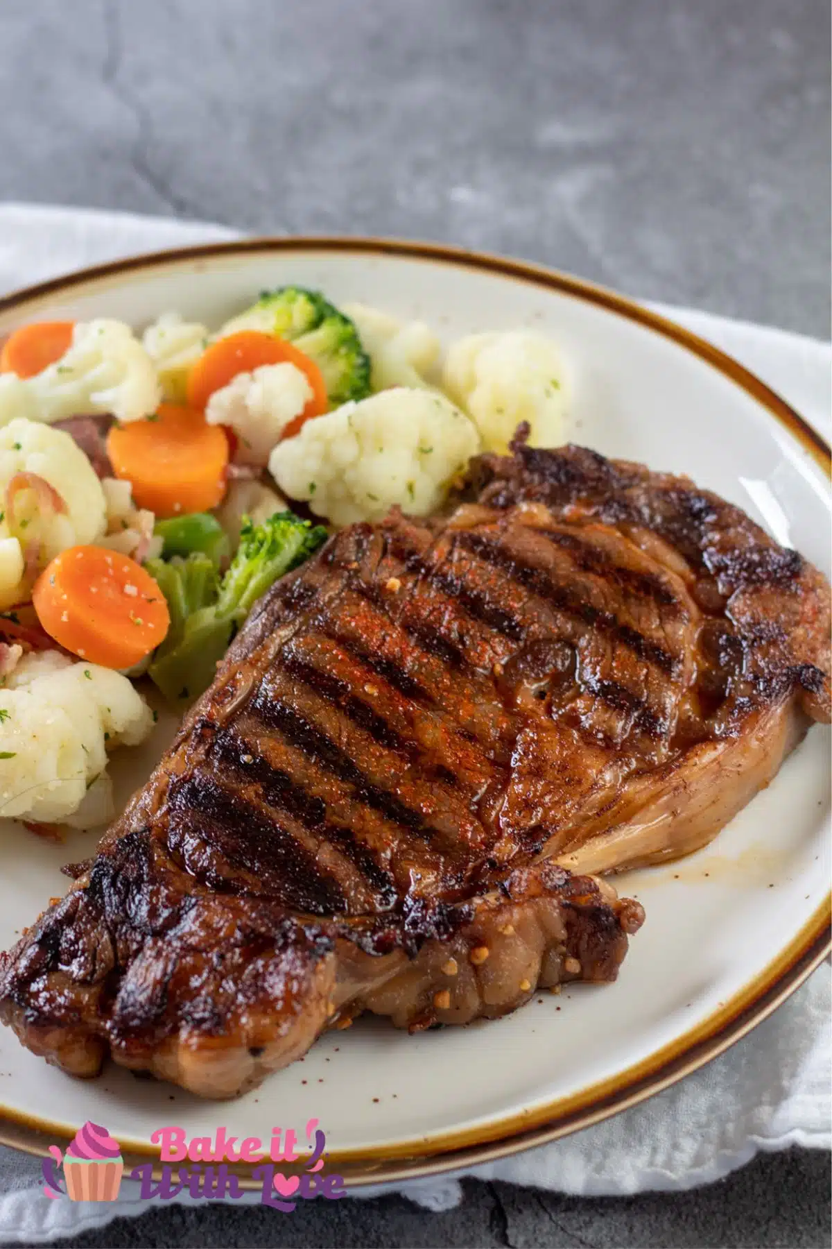 Tender grilled ribeye with steak marinade served on tan plate with veggie blend.