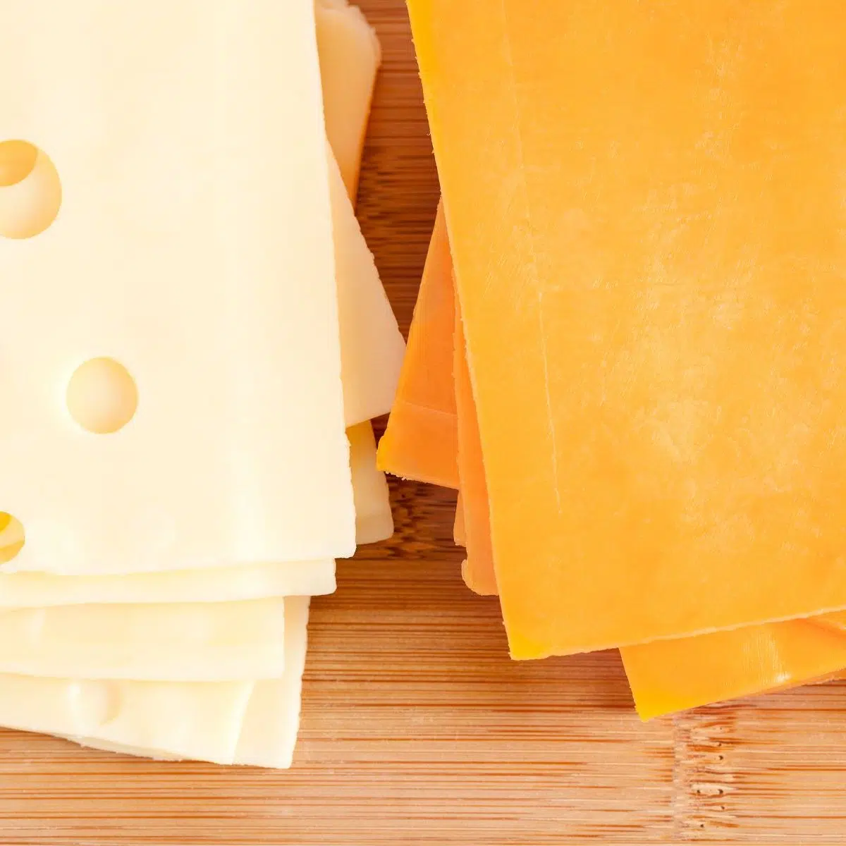 スライスしたチェダーチーズとスイスチーズを並べて比較したハンバーガーに最適なチーズ。