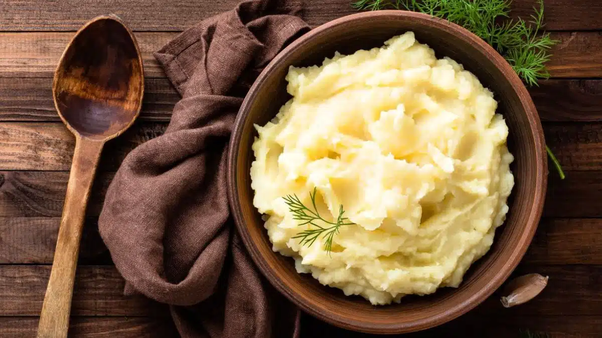 Wide overhead of the Instant pot mashed potatoes in wooden bowl with wooden background.