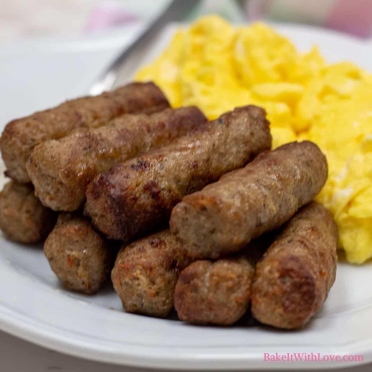 Square image of air fryer sausage links on a plate with scrambled eggs.