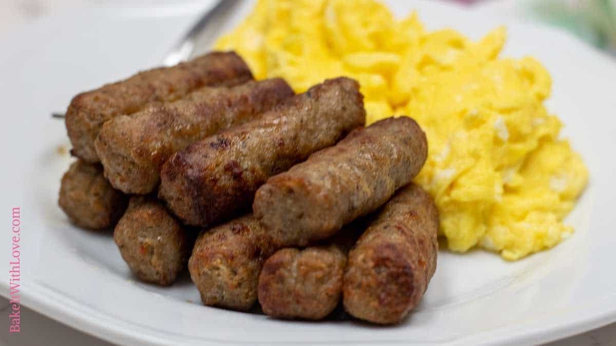 Wide image of air fryer sausage links on a plate with scrambled eggs.