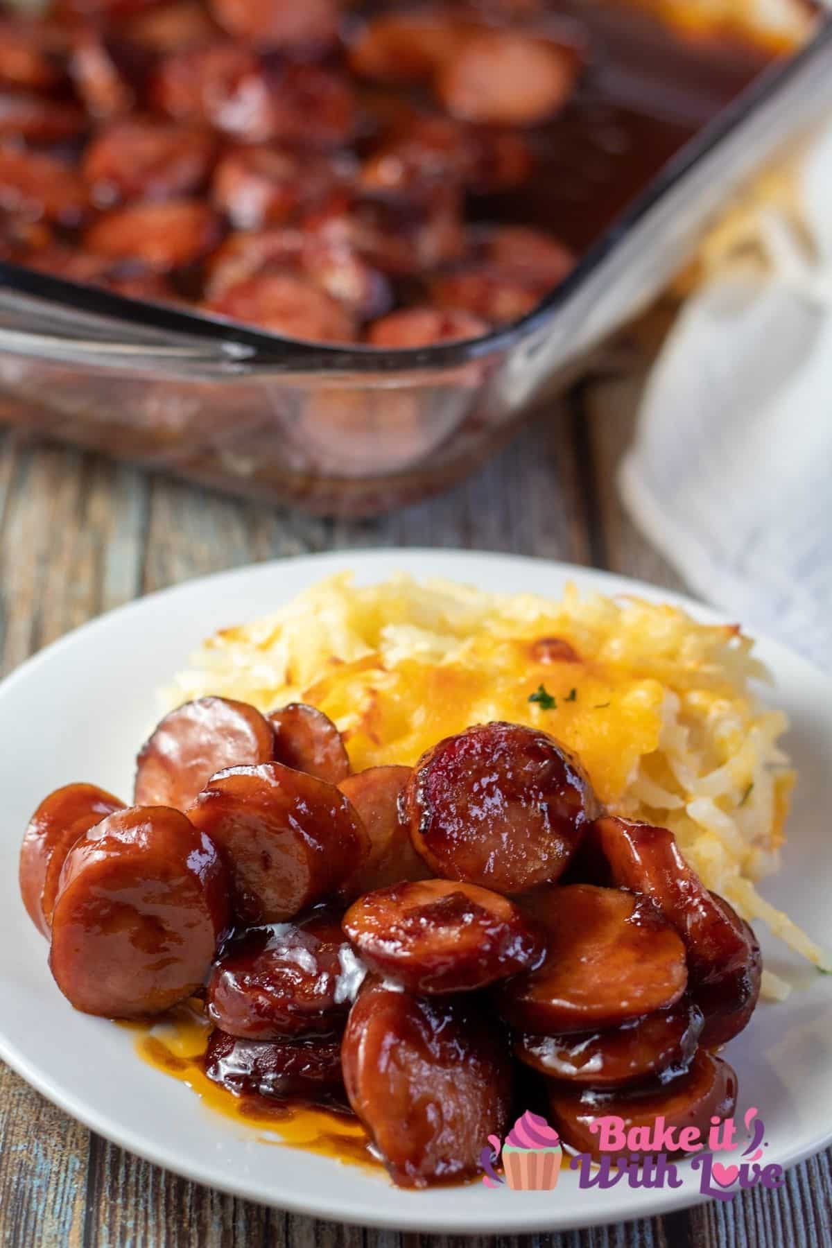Tall image of baked bbq sausages on a white plate.