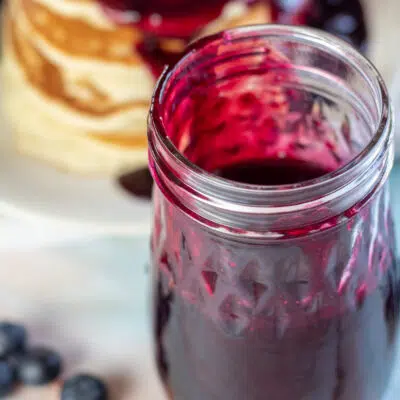 Square image of blueberry syrup in a jar.