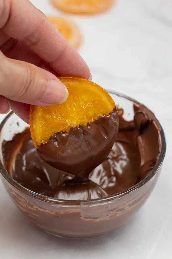 Process photo 9 showing candied orange being dipped in chocolate.