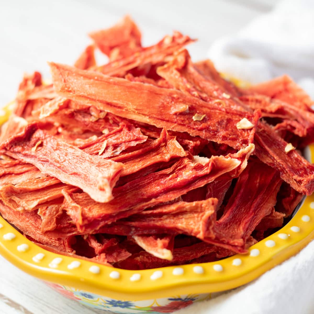 Easy, tasty dehydrated watermelon jerky in small serving bowl on light background.