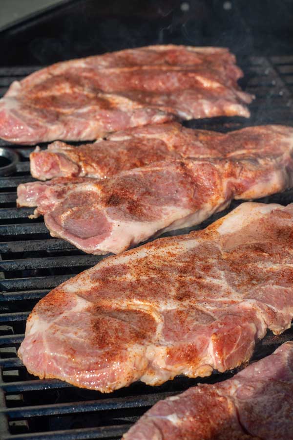 Fotoğrafı işleyin 4 terbiyeli domuz bifteklerini önceden ısıtılmış ızgaranıza aktarın.
