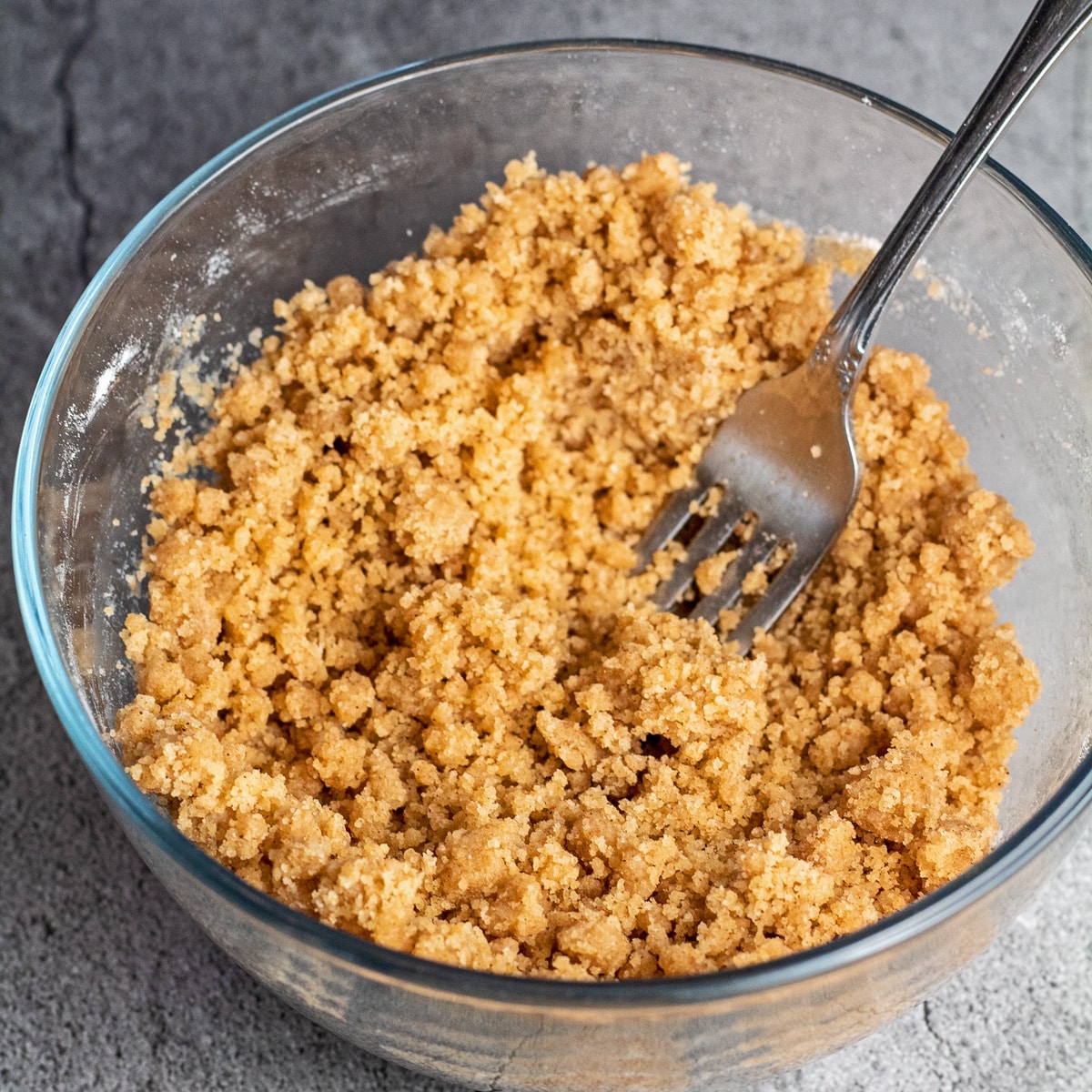 How to make a streusel crumb topping shown in clear glass bowl with fork after combining.