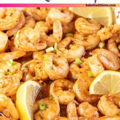 Pin image with text of new orleans bbq shrimp in pan with lemon slices.