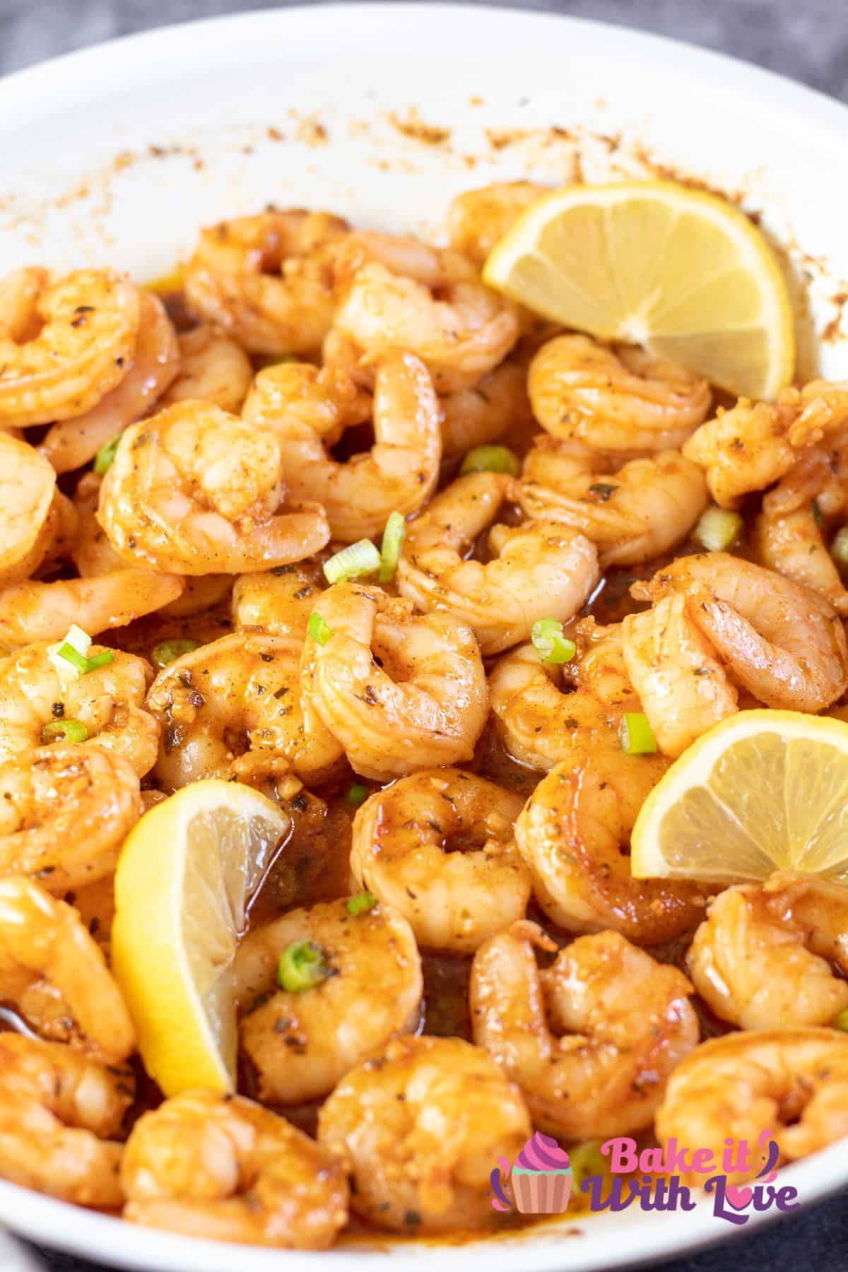 Tall image of new orleans bbq shrimp in pan with lemon slices.