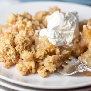 Close up square image of pear crisp on a white plate.