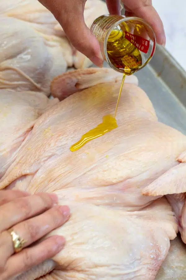Process image 5 showing drizzling olive oil over the skin of the chicken.