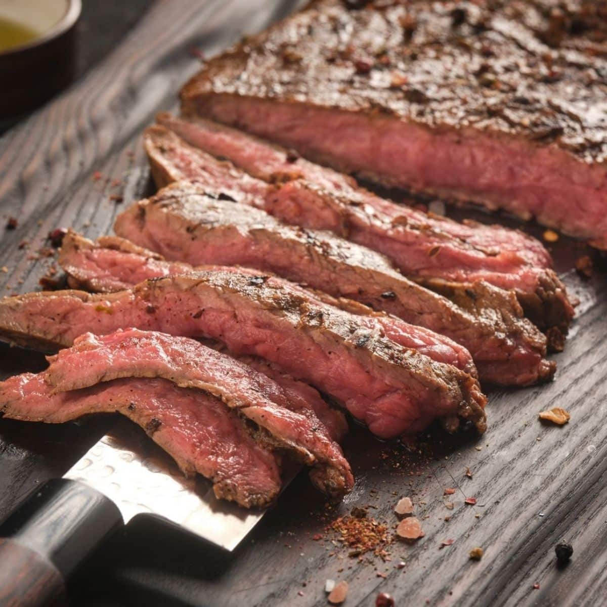 Steak bavette panggang mudah dihiris dan dihidangkan di atas papan pemotong kayu.