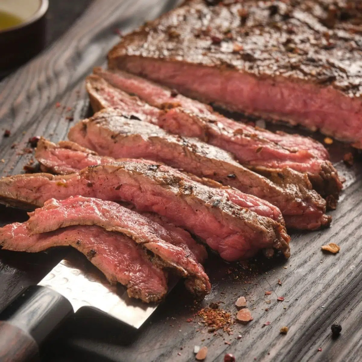 Steak bavette panggang yang mudah diiris dan disajikan di atas talenan kayu.