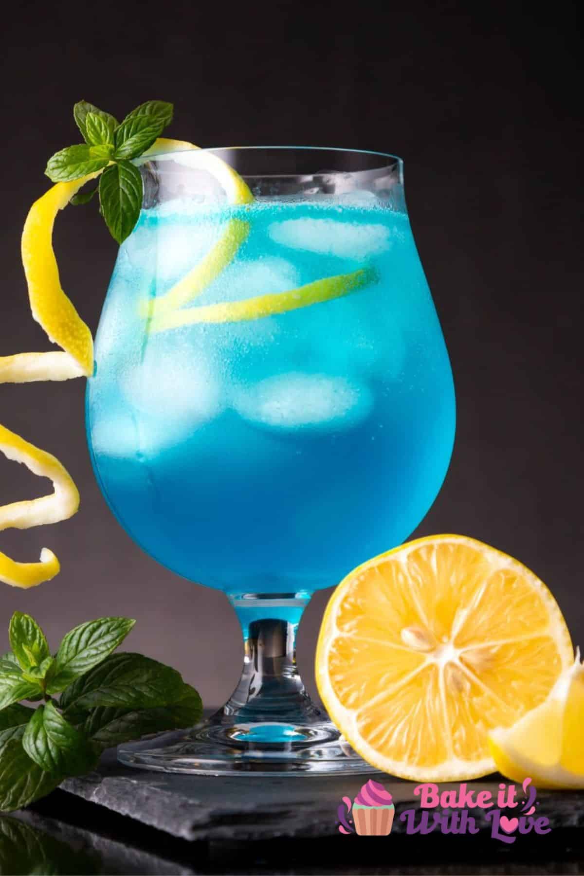 Tall closeup on the blue lagoon cocktail with sliced lemon and lemon twist.
