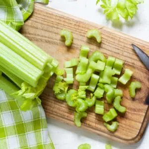 Best celery substitute ideas and alternatives illustrated with a fresh bundle of celery being chopped.