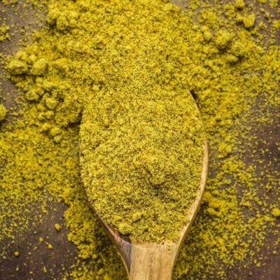 Best ground mustard powder substitute ideas and alternatives to use in cooking illustrated with ground mustard in wooden spoon.