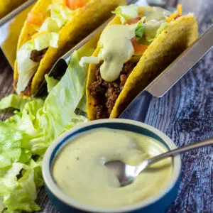 Square image of Taco Bell avocado ranch sauce with tacos.