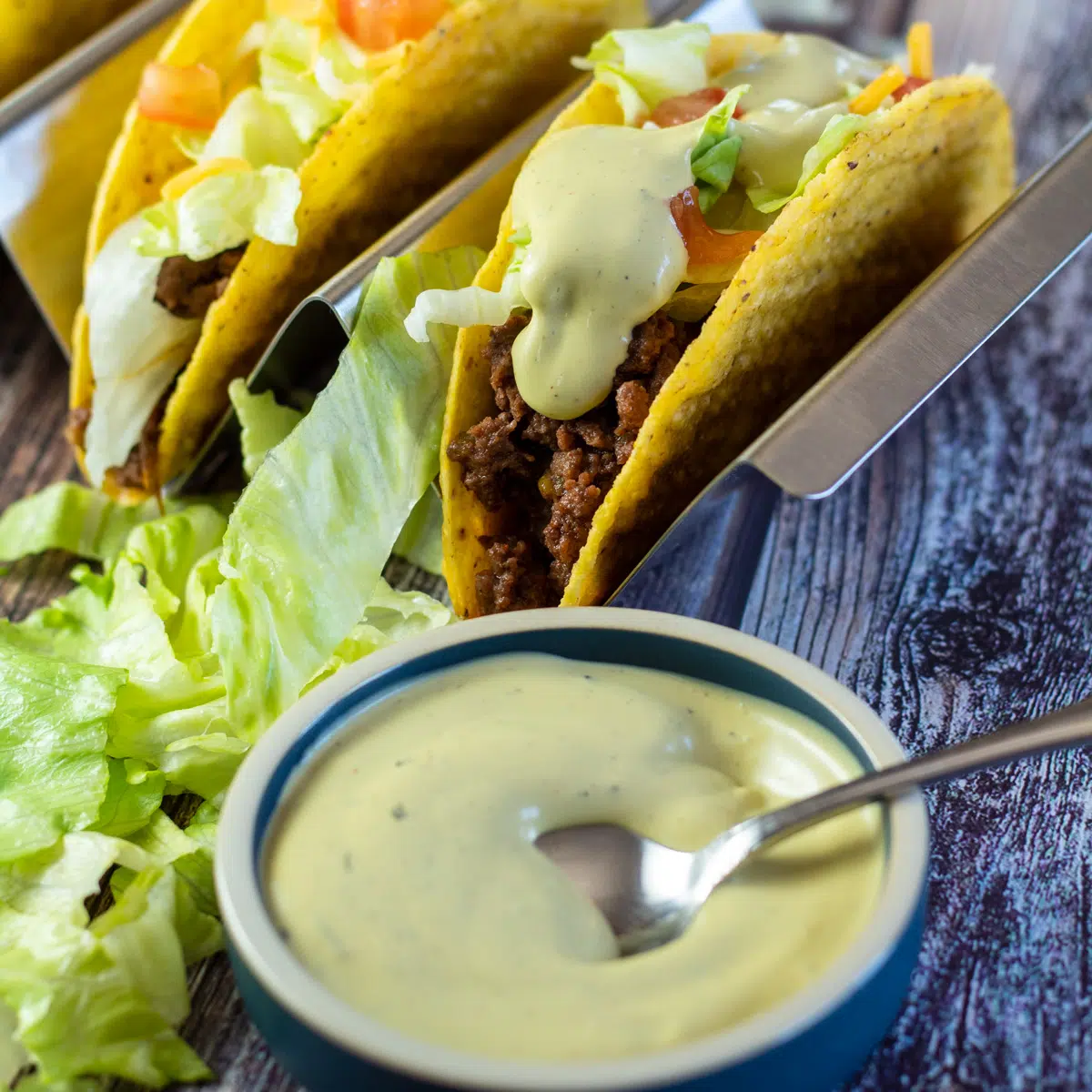 Firkantet billede af Taco Bell avocado ranch sauce med tacos.