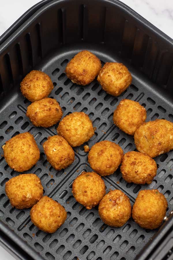 Process image 2 showing mac & cheese bites in the air fryer cooked at the half way point.