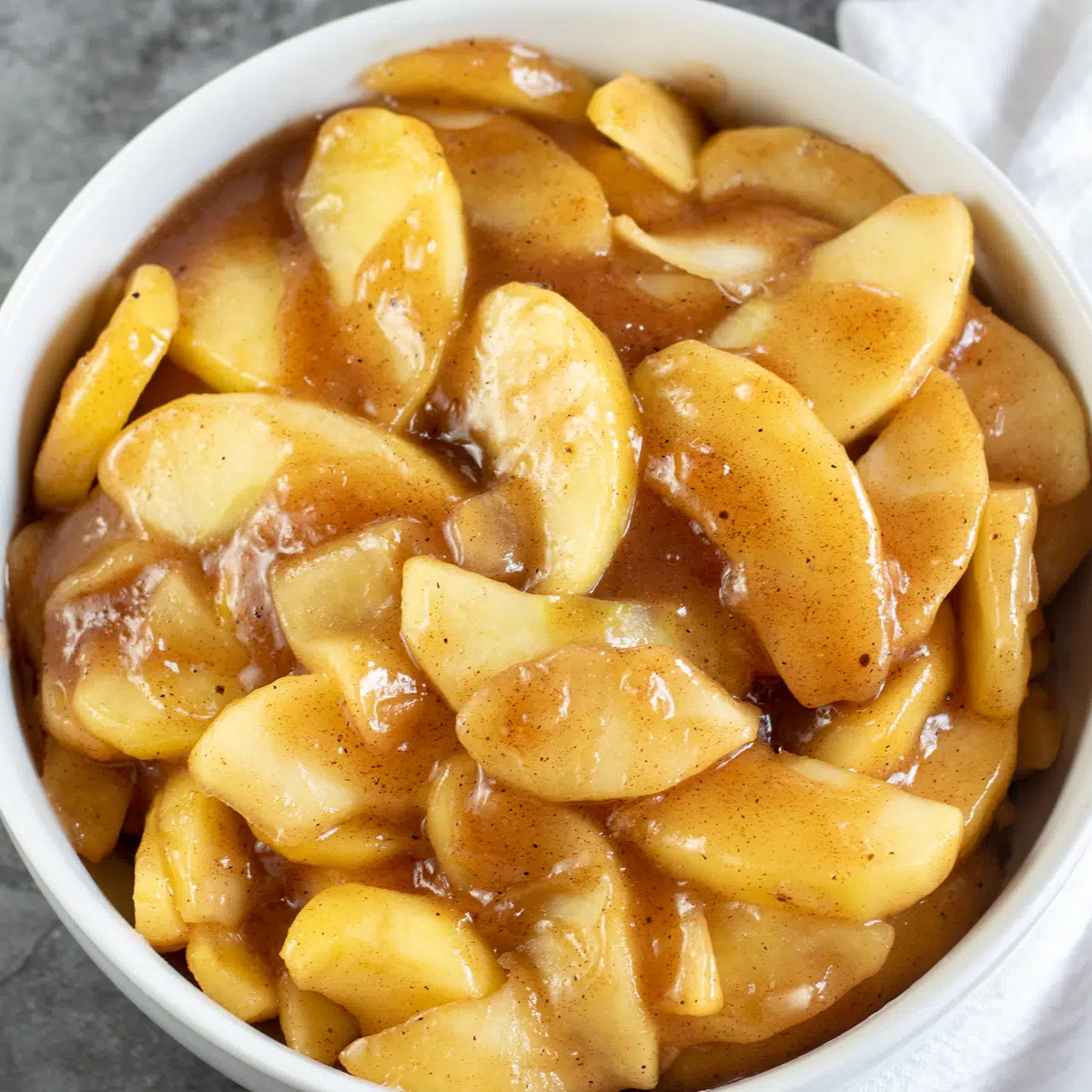 Imagen cuadrada de relleno de tarta de manzana en un recipiente blanco.