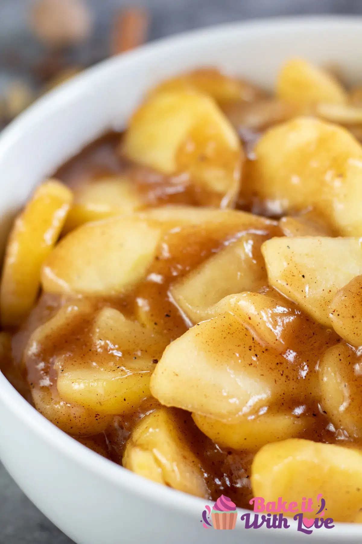 Tall image of apple pie filling in a white bowl.