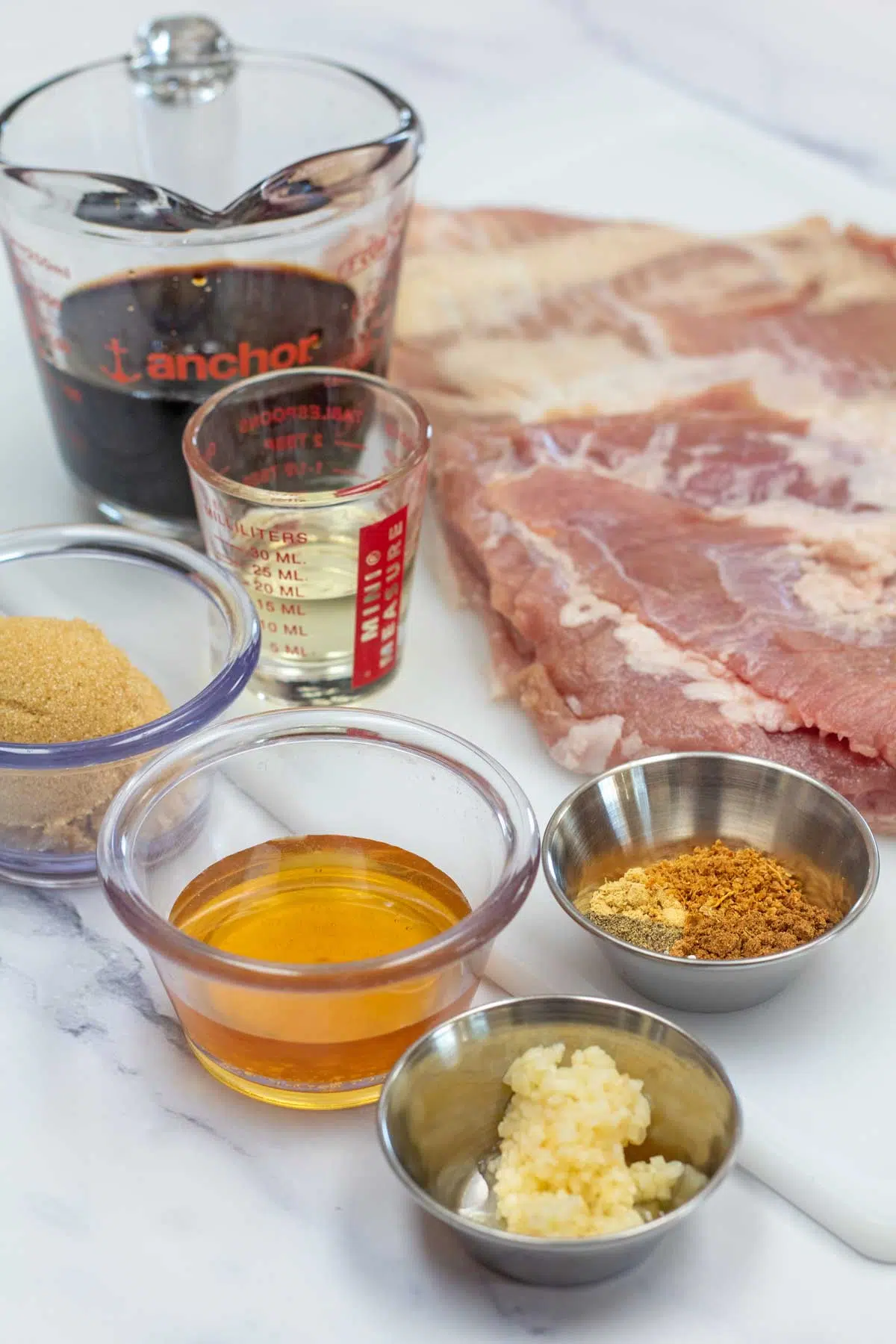 Tall image showing ingredients needed for roasted pork belly slices.