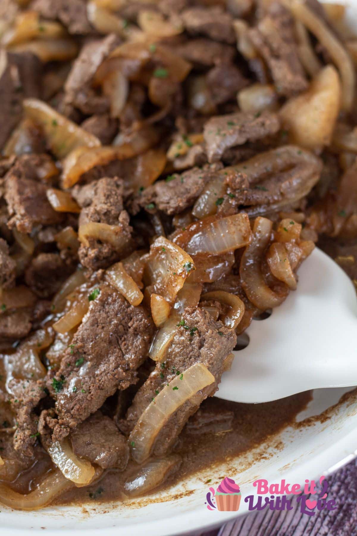 Tall image of beef liver and onions in a frying pan.
