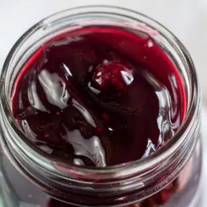 Square image of blackberry pie filling in a glass jar.