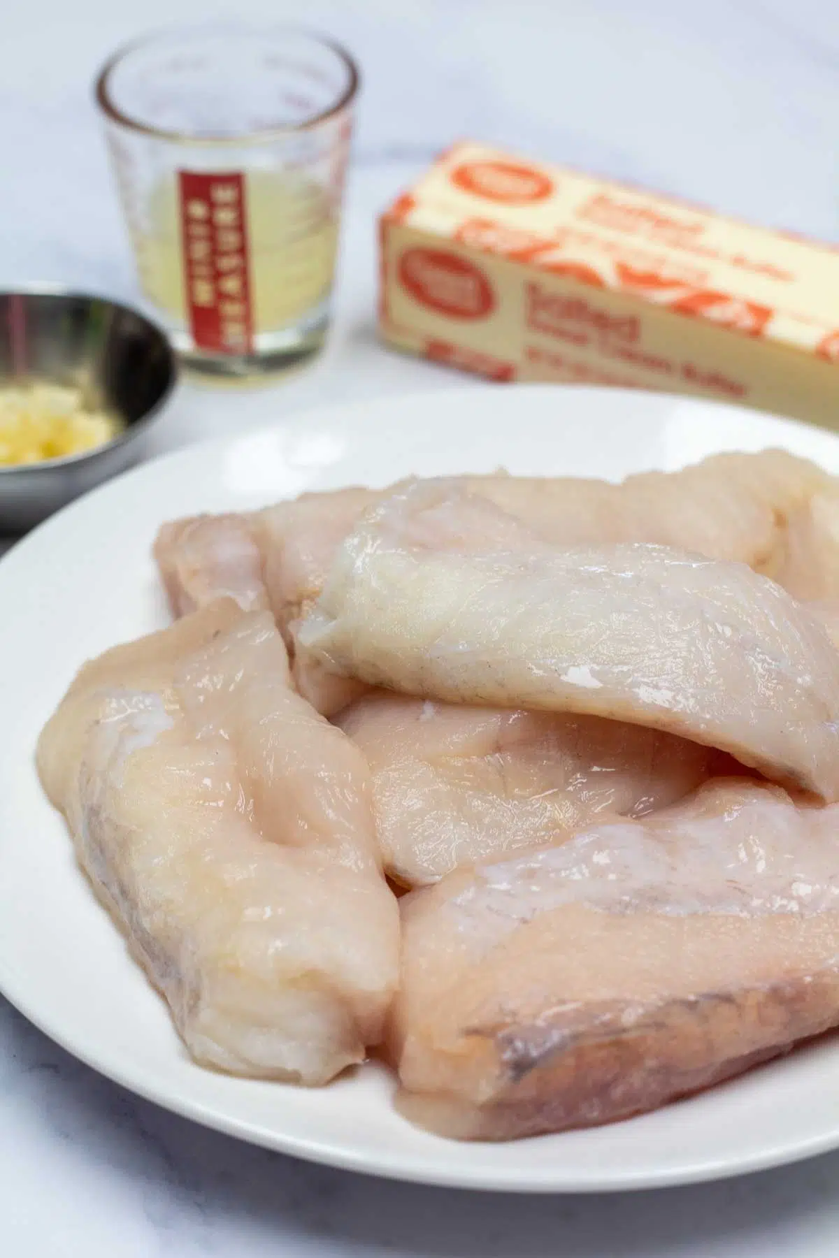Tall image showing the ingredients needed for butter poached monkfish.