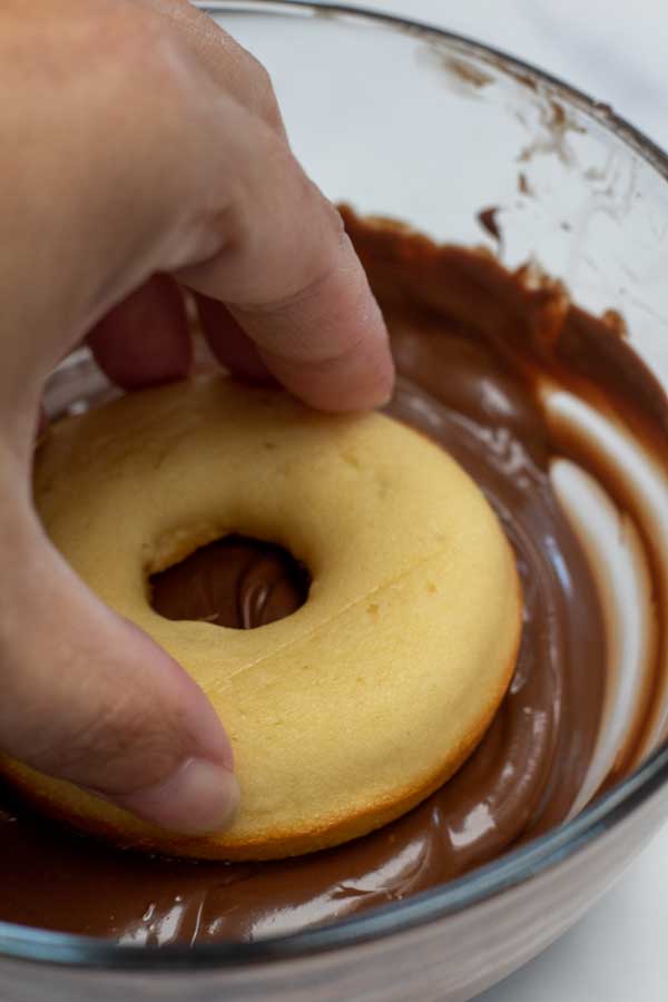 Process photo 4 showing coating a donut in the chocolate icing.