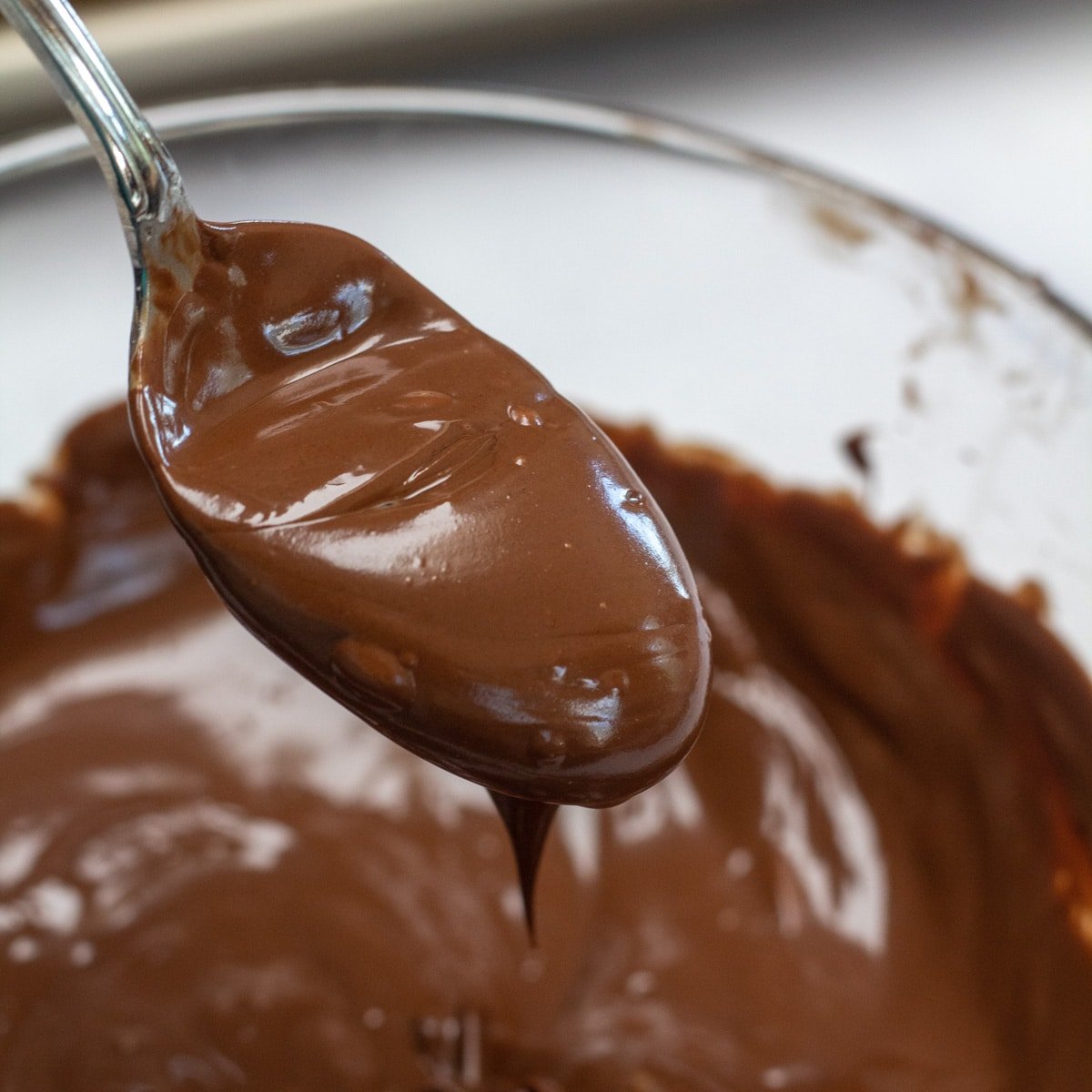 Квадратное изображение ложки шоколадной глазури для пончиков.