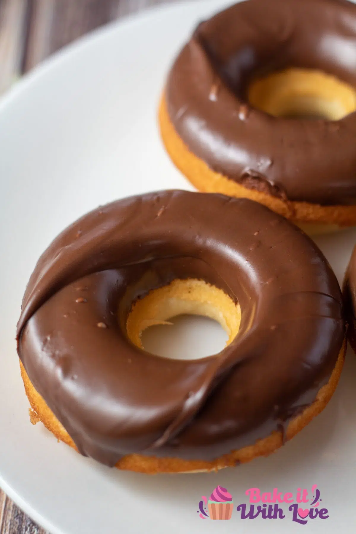 Tall image showing two donuts with chocolate icing.