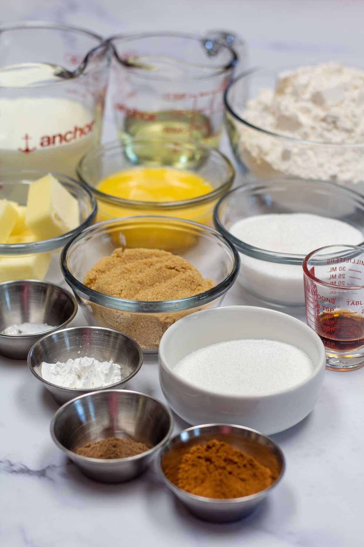 Tall image showing all the ingredients needed to make baked cinnamon sugar donuts.