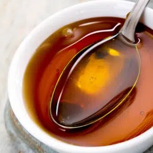 Square image of golden syrup in a small white bowl.