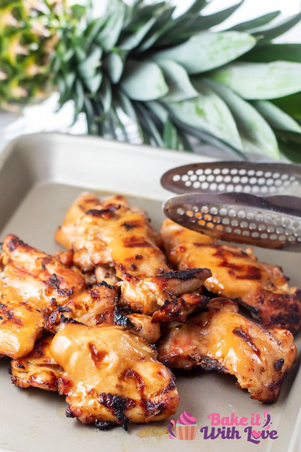 Tall image of teriyaki grilled boneless chicken thighs on a tray.