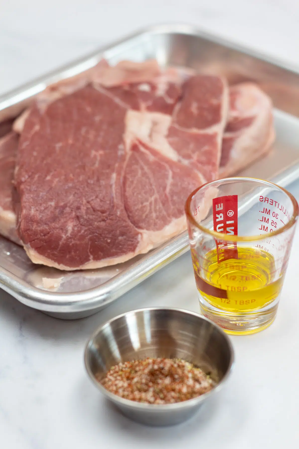 Tall photo showing ingredients needed for grilled lamb steaks.