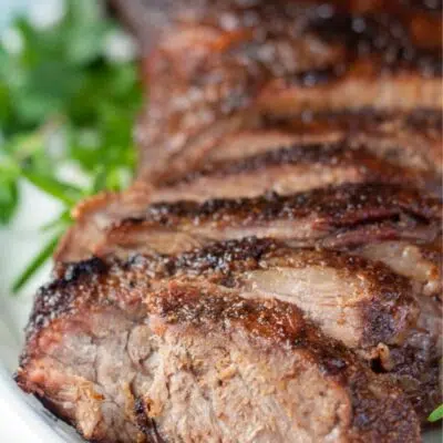 Pin image with text of sliced grilled beef tri-tip on a white serving platter.