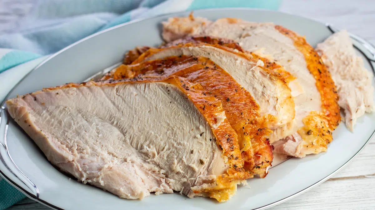 Sliced oven roasted turkey breast served on white platter.