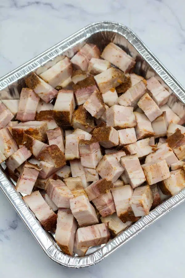 Process image 1 showing cut up cubed pork belly in a baking dish.