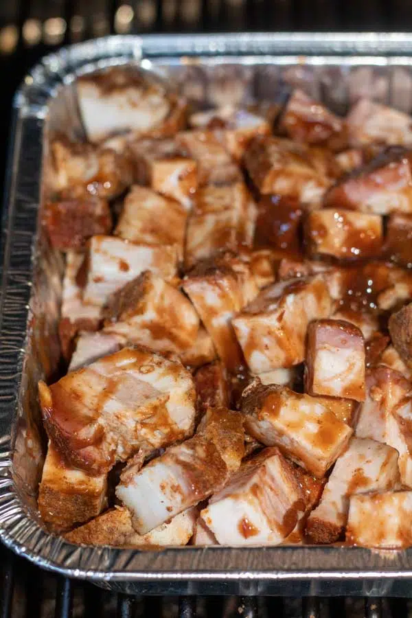 Process image 2 showing cut up cubed pork belly in a baking dish with bbq sauce over.