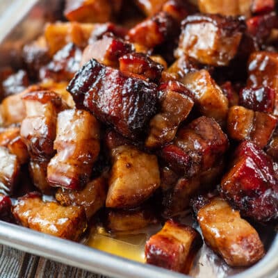 Square image of pork belly burnt ends on a small baking tray.